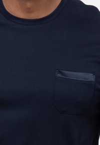 T-shirt blu navy a girocollo realizzato in cotone con un dettaglio a taschino testurizzato sul lato sinistro del petto. Tessuto liscio, maniche corte e design attillato.