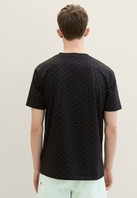 Black short-sleeve t-shirt with a subtle geometric pattern. Features a crew neck and a relaxed fit. Soft fabric with minimal texture.