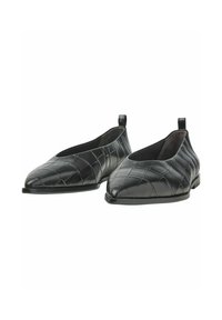 Chaussures en cuir noir avec une texture matelassée, à bout pointu et à profil bas. Dotées de boucles à l'arrière pour un enfilage et un retrait aisés.