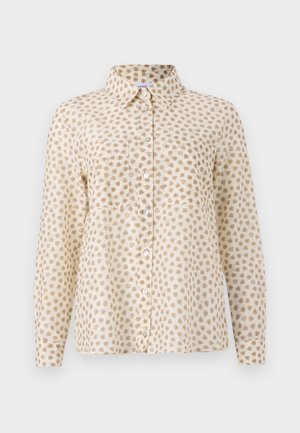 Chemise à manches longues en tissu beige clair, présentant un motif de pois marron répétitif, un col et un bouton sur le devant.