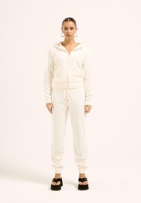 Krämlik huva zip-up sweatshirt och matchande joggers med ribbade manschetter, med subtila mönsterdetaljer, parat med svarta plattformssandaler.