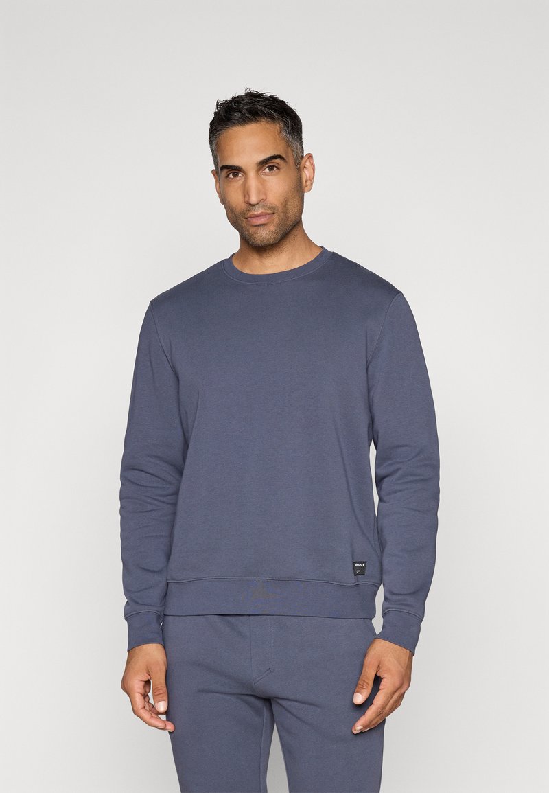 Σκούρο μπλε φούτερ με στρογγυλή λαιμόκοψη, μακριά μανίκια, ραμμένα μανίκια και στρίφωμα, με μια μικρή ετικέτα της μάρκας στην κάτω πλευρά. Μαλακή υφή υφάσματος.