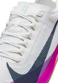 Chaussure de course Nike avec une tige en mesh blanc, des accents bleus et violets, et une semelle rose vif. Elle présente des lacets fins et des superpositions texturées.