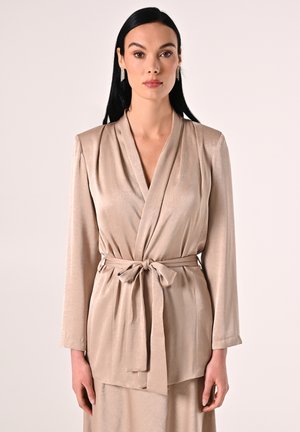 Beige, seidige Wickeljacke mit langen Ärmeln, tiefem V-Ausschnitt und gebundenem Taillenband. Glatte Textur mit dezentem Glanz und Drapierungsdesign.