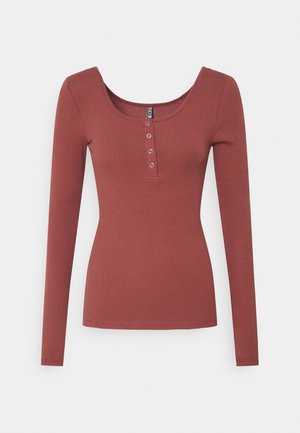 Top de manga larga acanalado en rosa empolvado con escote redondo, con cuatro botones contrastantes a lo largo de la tapeta. Textura de tela suave.