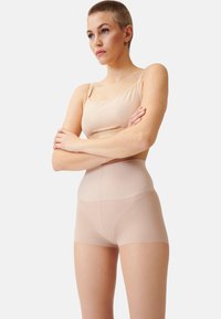 Nude nahtloses hochgeschnittenes Shapewear mit einer glatten, dehnbaren Textur und breitem Bund, entworfen für Komfort und Abdeckung.