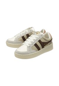 Sneakers con una tomaia in pelle bianca, accenti in camoscio grigio e strisce marroni. La suola in gomma presenta un battistrada testurizzato. Dettagli del logo dorato.