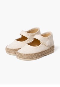 Light beige canvas shoes with a rounded toe, elastic strap, and a jute-like textured sole. Features a smooth interior lining.
