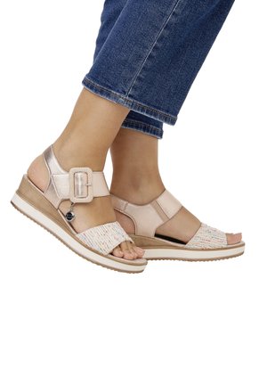 Two wedge sandals featuring a pink leather upper, textured woven fabric strap, adjustable buckle, and a light-colored sole with tread.