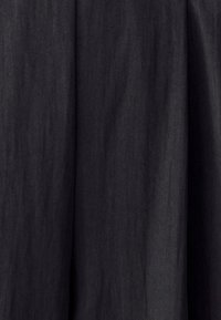 Schwarzer Stoff mit einer weichen Textur und subtilen vertikalen Falten, die sanfte Schatten und Tiefe erzeugen.