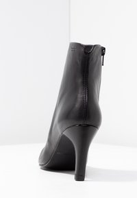 Stivale alla caviglia in pelle nera con un design elegante, punta affusolata, zip laterale e tacco alto. Finitura testurizzata con dettagli di cucitura sottili.