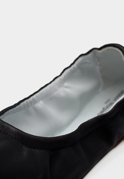 Κοντινό πλάνο ενός μαύρου δερμάτινου μπαλαρίνα παπουτσιού με μαλακό, ελαστικό περιθώριο και εσωτερική επένδυση σε ανοιχτό γκρι, μαξιλαρωμένη.
