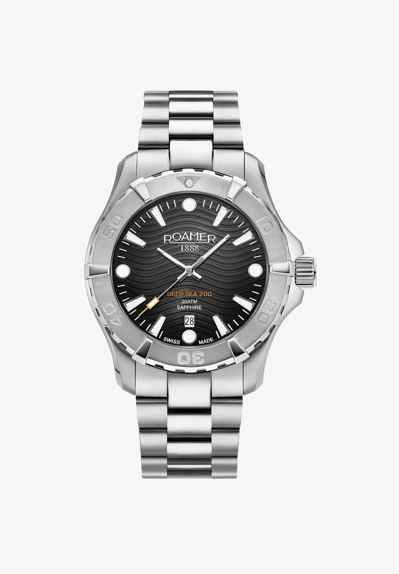 Montre en acier inoxydable avec un cadran noir texturé, des index d'heure lumineux, des accents orange et un affichage de la date à 6 heures. Résistante à l'eau jusqu'à 200 mètres.