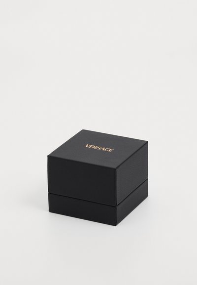 Boîte carrée noire en matériau texturé avec un logo "VERSACE" doré sur le dessus. Présente un couvercle qui s'adapte parfaitement à la base.
