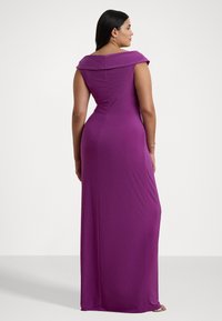 Lungo vestito viola con scollo off-the-shoulder, design aderente e texture liscia, che scende fino a terra in una silhouette dritta.