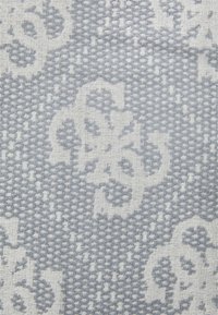 Textile présentant un motif texturé avec des motifs floraux gris clair sur un fond gris foncé. Le matériau affiche des détails tissés.