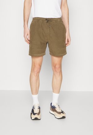 Brązowe męskie szorty sztruksowe z elastycznym pasem, ściągaczem na sznurek i bocznymi kieszeniami, w zestawie z białymi skarpetami i tenisówkami.