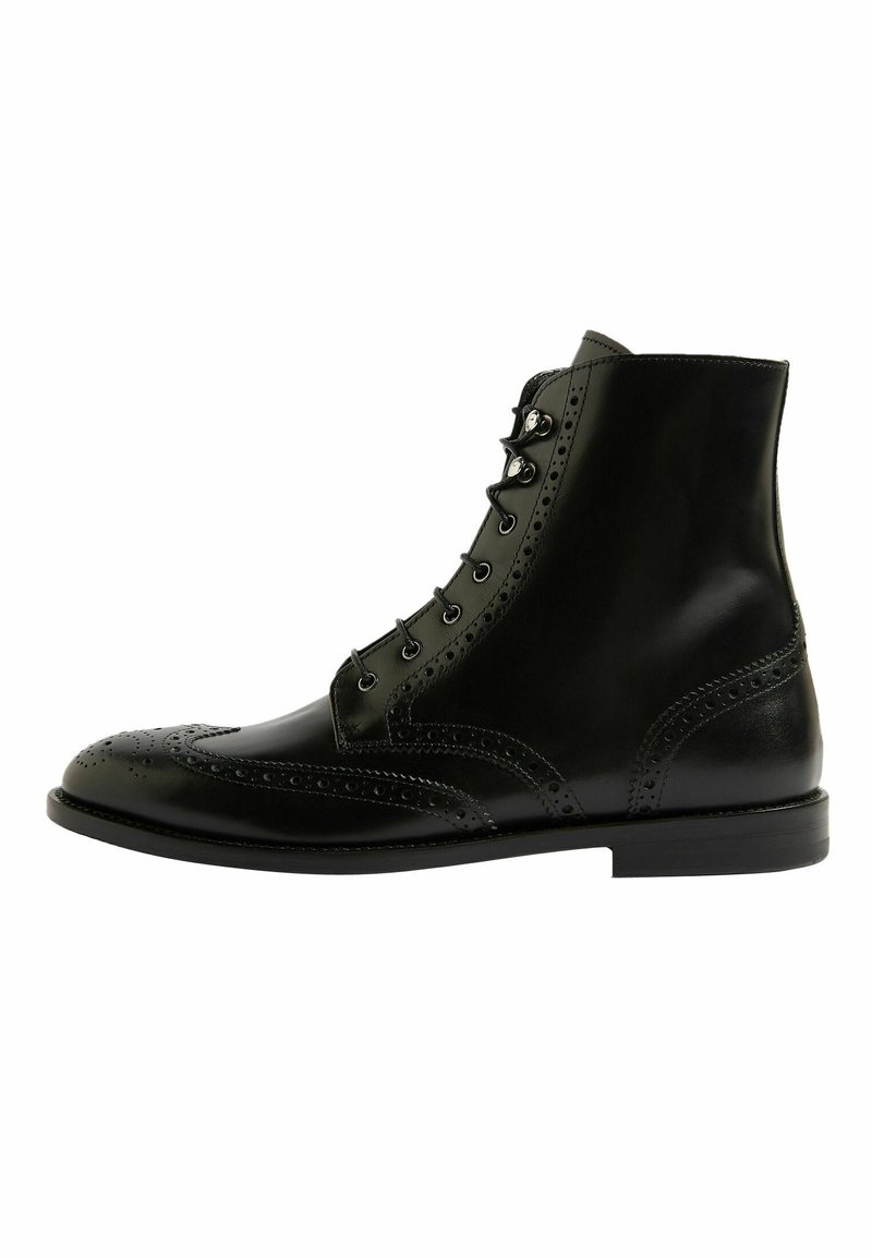 Stivaletto in pelle nera con dettagli brogue, punta rotonda, lacci frontali e una texture liscia con tacco stacked a profilo basso.