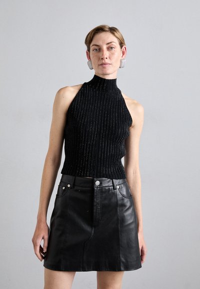 Top negro sin mangas de punto acanalado con cuello alto, combinado con una falda mini de cuero negra que cuenta con bolsillos frontales y acentos metálicos.