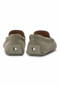 Suedes slip-on sko i olivengrøn med blød tekstur, rund form og kontrasterende logo detaljer på hælen. Fremstillet i Portugal.