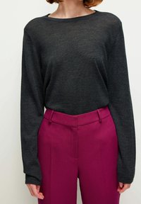 Tummanharmaa, pitkähihaista pehmeää materiaalia oleva neule, yhdistetty kirkkaan fuksianvärisiin, korkeavyötäröisiin housuihin, joissa on räätälöity istuvuus ja eteen laskokset.