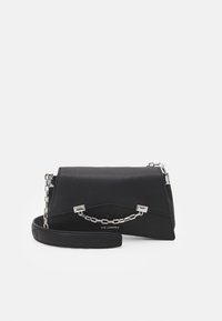 Czarna skórzana torebka o wyraźnie zarysowanym kształcie, z akcentem srebrnego łańcuszka i krótkim paskiem. Teksturowana powierzchnia z delikatnym ziarnem.