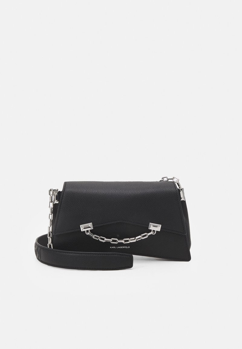 Černá kožená kabelka s pevnou strukturou, zdobená stříbrným řetízkem a krátkým popruhem. Texturovaný povrch s jemnou texturou zrna.