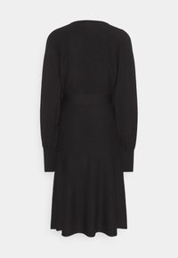 Robe midi noire à manches longues avec taille cintrée et jupe légèrement évasée, vue de dos sur fond uni.