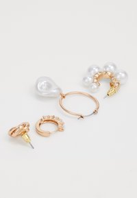 Set di quattro orecchini: due orecchini a cerchio in tonalità oro, uno con accenti di perle; un orecchino pendente in oro texturizzato; una goccia bianca liscia; dimensioni e design vari. 