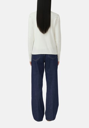 Weißes Langarmshirt kombiniert mit dunkelblauen, weit geschnittenen Jeans. Das Oberteil hat eine glatte Textur, während die Jeans ein klassisches Denim-Finish aufweisen.