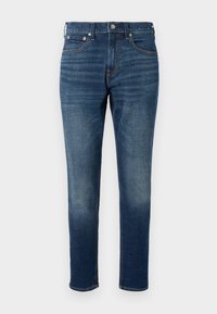 Σκούρα μπλε τζιν παντελόνια με στενή εφαρμογή, σχεδίαση πέντε τσεπών, αντίθετη πορτοκαλί ραφή και φερμουάρ με μεταλλικό κούμπωμα.