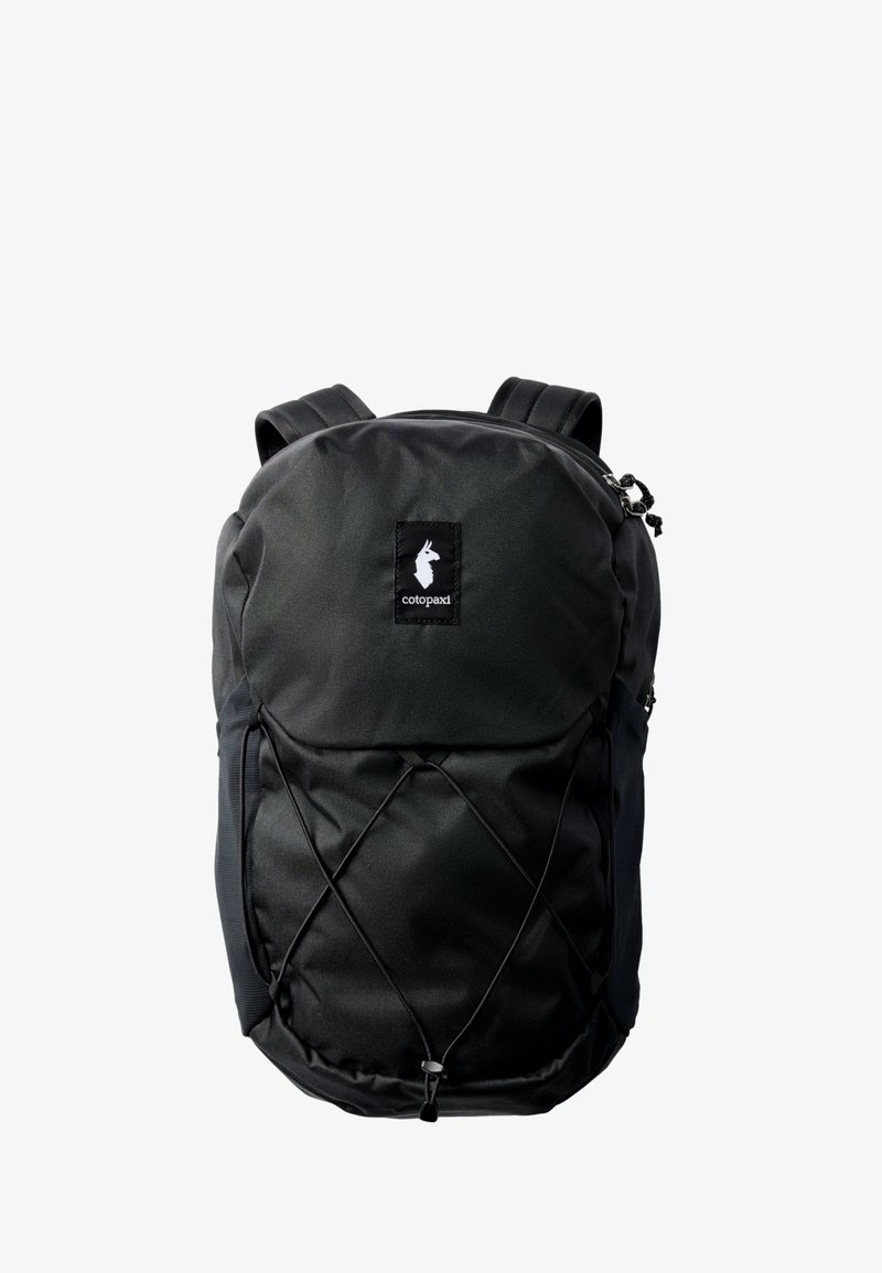 Black Cotopaxi backpack with front elastic bungee cord, zippered top compartment, and padded shoulder straps on a white background.
