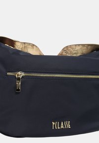 Borsa in nylon blu navy con zip dorata, dotata di apertura superiore e interni a motivo beige. Logo in oro sulla parte anteriore.