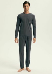 Szary longsleeve z dekoltem w kształcie V i pasującymi spodniami piżamowymi wykonanymi z miękkiego materiału. Top zapewnia luźny krój przez cały czas noszenia.