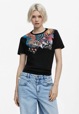 Black cotton t-shirt featuring a colorful butterfly design on the shoulder, with a round neckline and short sleeves. Paired with light blue denim jeans.