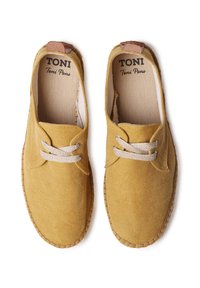 Scarpe da ginnastica gialle in tela con lacci beige e un accento in pelle marrone sul tallone. Presentano una punta arrotondata e suola cucita.