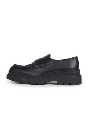 Zwarte leren loafer met dikke profielzool en lage hak, slip-on ontwerp en gestikte bovenkant, zijaanzicht op witte achtergrond.