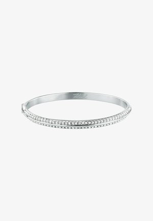 Bracelet jonc argenté avec deux rangées de petits cristaux clairs le long du bord extérieur sur fond blanc.