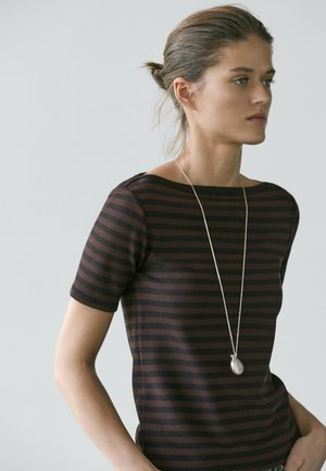 Pruhovaný top s krátkým rukávem v tmavě hnědé a černé látce, s lodičkovým výstřihem. Nositelný s dlouhým stříbrným přívěskem na náhrdelníku.