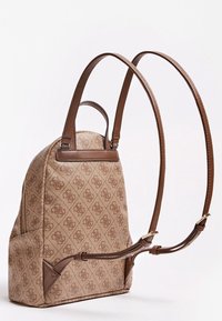 Ruskea kuvioitu reppu, jossa on nahkaremmit ja kultaista sävyä olevat soljet, nähtynä sivulta valkoista taustaa vasten.