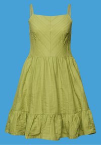 Robe d'été vert clair sans manches avec fines bretelles, corsage ajusté présentant des surpiqûres en chevrons subtiles, et un ourlet à volants sur un fond bleu.