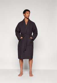 Black textured bathrobe with wide sleeves, front pockets, and a matching belt, featuring a knee-length cut and a classic design.