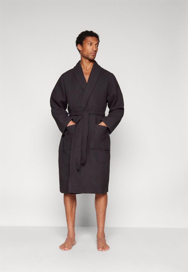 Black textured bathrobe with wide sleeves, front pockets, and a matching belt, featuring a knee-length cut and a classic design.
