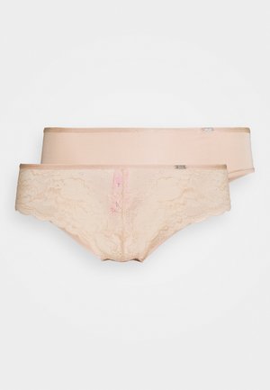 Twee paar damesondergoed in een licht nude tint. Een paar heeft een kanten ontwerp, terwijl het andere een gladde afwerking heeft. Beide hebben een gegolfde rand.