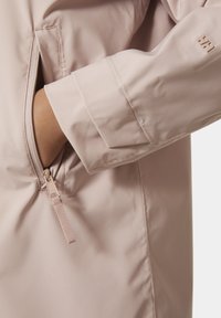 Světle růžová voděodolná bunda s zipovou kapsou, hladkou texturou a akcentem na zahnuto hrdla s logem na rukávu.