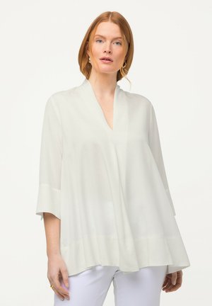 Bílá blůza s výstřihem do V, kimono rukávy a volný silueta. Vyrobena z lehkého, průsvitného materiálu. Hladký povrch.