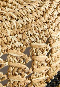 Cesta de almacenamiento tejida hecha de fibras naturales en colores beige y crema, con un patrón de tejido abierto y un acabado texturizado y robusto.