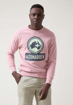 Sudadera rosa claro con un logo redondo que presenta una silueta y el texto "ALTONADOCK" en el pecho. Material de algodón, puños acanalados.