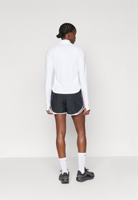 Pikkade varrukatega valge spordipehme kõrge kaelusega, koos mustade spordilühikestega, millel on valged küljeäärised. Mustad jooksujalanõud ja valged sokid.