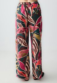 Pantaloni ampi con una vivace stampa a foglia che presenta tonalità di rosa, verde e oro su uno sfondo chiaro. Vita elastica, stoffa morbida, senza tasche.